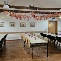 Saal mit Geburtstagsgirlande und langer gedeckter Tafel