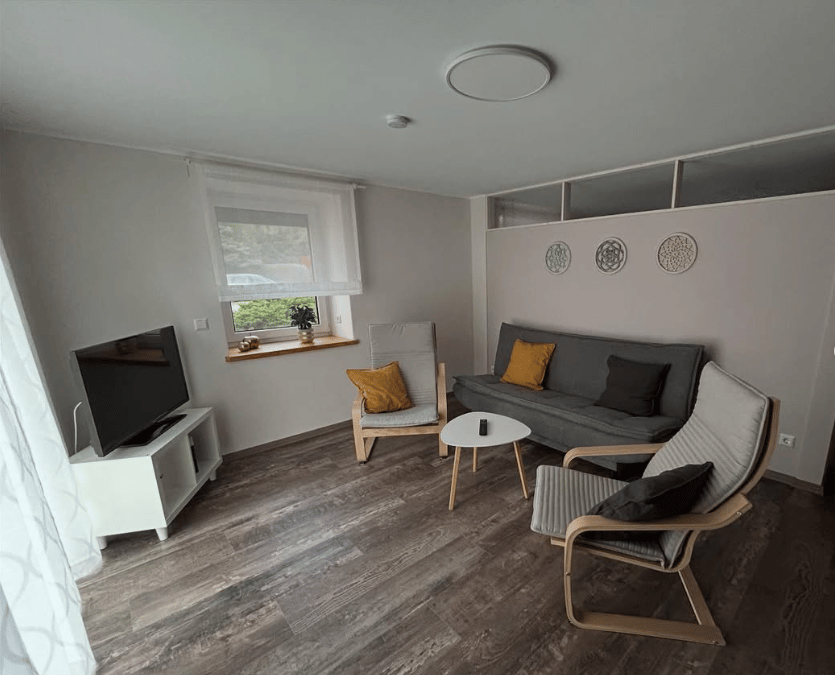 Wohnraum der Ferienwohnung Hentschel mit Sofa, Sessel und Fenster